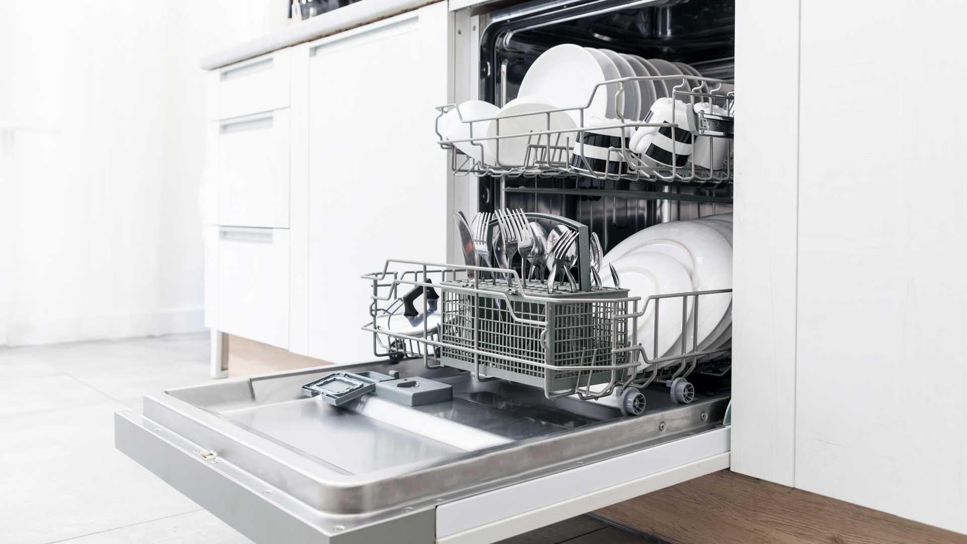 Brightly lit dishwasher full of clean dishes